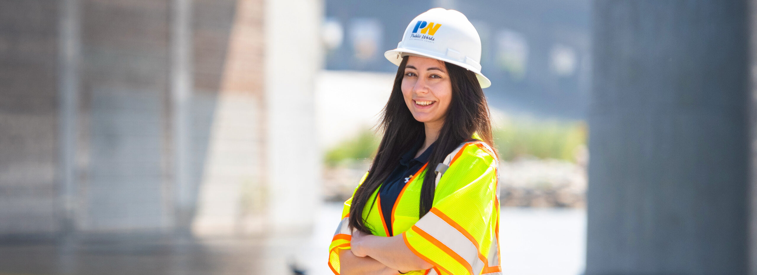 Employee crossing their arms and wearing a hard hat and safety vest